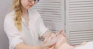 Beautician performs facial massage. Young beautiful woman lies on spa bed get beauty treatments