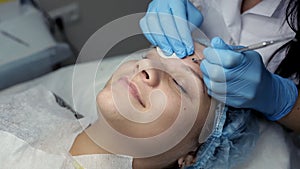 The beautician pierces the needle with the needle on the girl`s face. The procedure of mechanical face cleaning