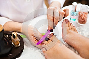 Beautician polishing nails, pedicure. Foot care treatment and na