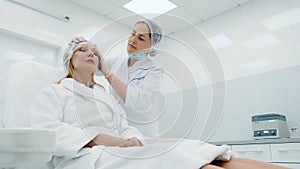 Beautician prepares a woman to procedures in a cosmetology clinic