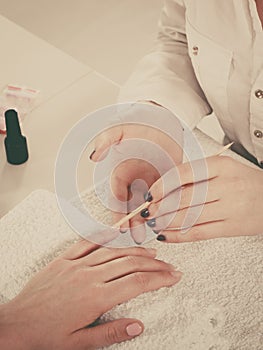 Beautician preparing nails before manicure, pushing back cuticles