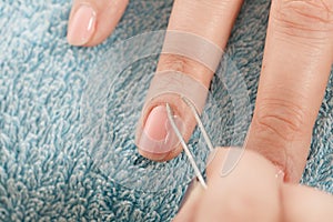 Beautician preparing nails before manicure, pushing back cuticles