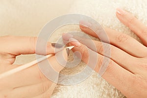 Beautician preparing nails before manicure, pushing back cuticles photo