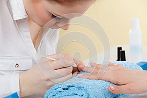 Beautician preparing nails before manicure, pushing back cuticles photo