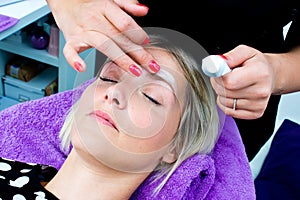 Beautician putting skin cream on woman face