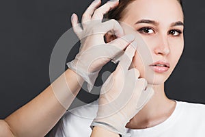 Beautician removes the mask from the face of a young beautiful girl, on a gray background, the concept of rejuvenation