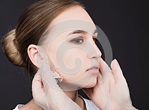 Beautician removes the mask from the face of a young beautiful girl, on a gray background, the concept of rejuvenation