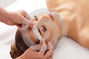 Beautician is removing hair from beautiful female face with hot wax. Woman has a beauty treament procedure. Depilation