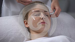 Beautician removing remains of mask from girls face, deep cleaning of pores