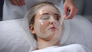 Beautician removing remains of mask from girls face, deep cleaning of pores