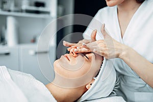 Beautician rubs the cream on female patient face