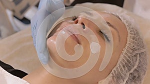 Beautician rubs the cream on woman`s face