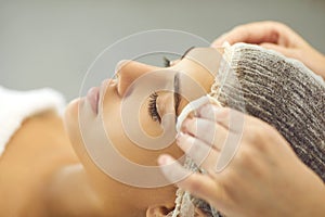 Beautician`s hands are wiping the woman`s face with a cotton pad in a beauty salon.