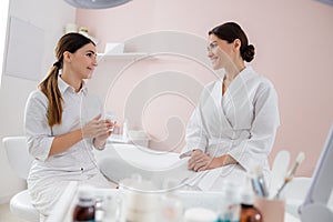 Beautician talking with young woman at wellness center