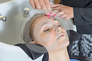 Beautician trimming a young girls eyebrows