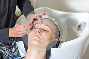 Beautician trimming a young girls eyebrows