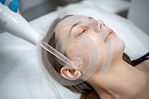 Beautician uses the darsonval device on the client& x27;s face. Professional skin care in the salon. The concept of