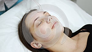 Beautician uses the darsonval device on the client's face. Professional skin care in the salon. The concept of