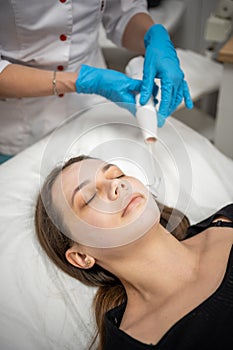 Beautician uses the darsonval device on the client& x27;s face. Professional skin care in the salon. The concept of