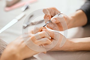 Beautician using cuticle pusher on woman hand photo