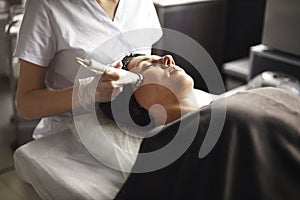 Beautician using machine for radiofrequency lifting