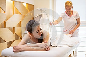 Beautician waxing leg of woman with wax strip at a beauty spa.