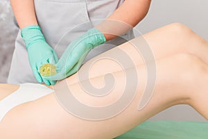Beautician waxing legs of woman