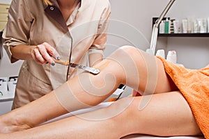 Beautician waxing a woman's leg