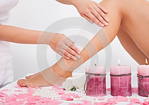 Beautician waxing a woman's leg