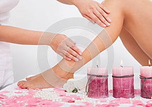 Beautician waxing a woman's leg photo