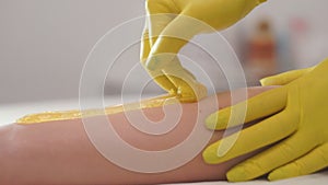 Beautician waxing woman`s leg in beauty spa. Procedure for legs shugaring.