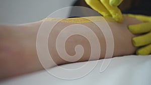 Beautician waxing woman`s leg in beauty spa. Procedure for legs shugaring.