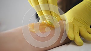 Beautician waxing woman`s leg in beauty spa. Procedure for legs shugaring.