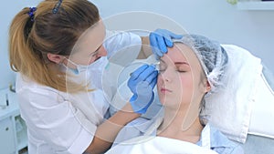 Beautician is wiping eyebrows using cotton pads making eyebrows microblading.