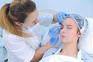 Beautician is wiping eyebrows using cotton pads making eyebrows microblading.