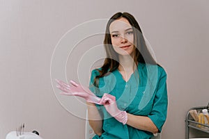 Beautician woman putting on pink rubber gloves