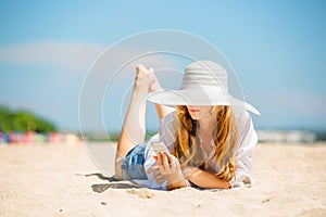 Beautifil young woman lying on the beach at sunny