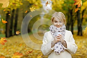 Beautifl blonde girl holding cup of hot tea in beautiful autumn