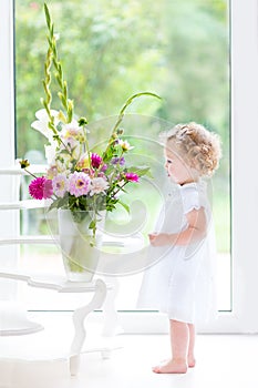 Beautifl toddler girl watching flowers in a big vase photo