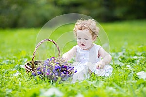 Beautifu baby girl with blond curly hair wearing a white dress