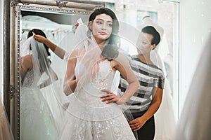 Beautifu bride choosing wedding dress in a wedding salon