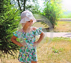 Beautifu child girl in a fashionable summer sundress in the park