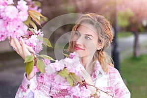 Beautiful 30s woman holding cherry blossom at springtime portrait