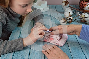 Beautiful 8 year old blond granddaughter doing manicures with nail polish grandmother at home