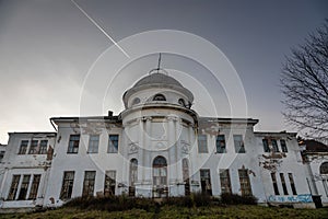 A beautiful abandoned manor house with a white facade. Evening light.