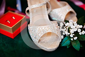 Beautiful accessories of the bride..Sandals, wedding rings, flowers on an emerald chair