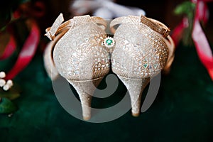 Beautiful accessories of the bride..Sandals, wedding rings, flowers on an emerald chair