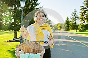Beautiful active mature woman with bike on the road in the park