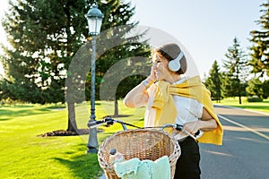 Beautiful active mature woman with bike on the road in the park