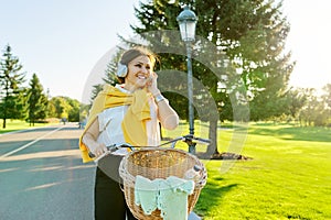 Beautiful active mature woman with bike on the road in the park